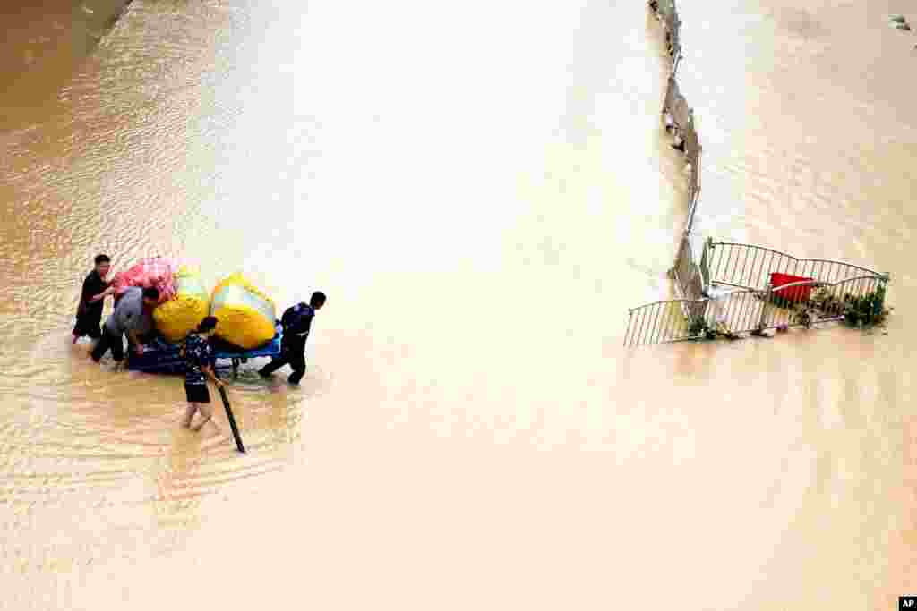 Residents move their belongings across a flooded street in Zhengzhou in central China&#39;s Henan province. (Credit:&#160;Xinhua News Agency)