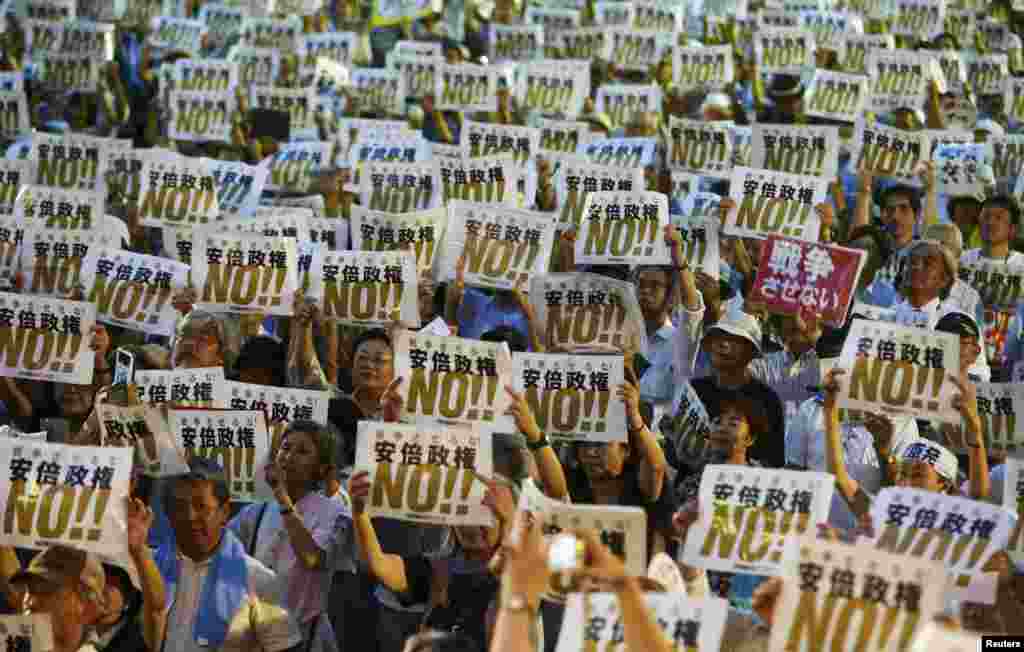 People hold placards denouncing Japan&#39;s Prime Minister Shinzo Abe&#39;s security-related legislation during an anti-government rally in Tokyo.&nbsp; Abe pushed legislation through parliament&#39;s lower house that could see troops sent to fight abroad for the first time since World War II.