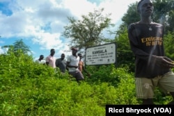 Residents of nearby Durabali, Guinea-Bissau, walk past the entrance sign to the site of the now-gone city of Kansala, the capital of the Kingdom of Kaabu, on Sept. 24, 2024.