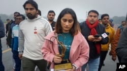 Indian wrestler Vinesh Phogat, a two-time World Championship medal winner, walks with her national sports awards before leaving them on a pavement near the prime minister's office as a mark of protest in New Delhi, India, Dec. 30, 2023.