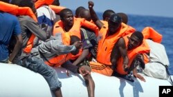 FILE - Migrants wearing life vests float in an inflatable boat during a rescue operation from the Aquarius vessel of SOS Mediterranee NGO and MSF (Doctors Without Borders) in the sea some 25 Nautical miles (29 miles, 46 kilometers) north of the Libyan coast, Aug. 27, 2017.