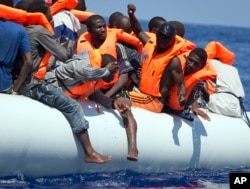 FILE - Migrants wearing life vests float in an inflatable boat during a rescue operation from the Aquarius vessel of SOS Mediterranee NGO and MSF (Doctors Without Borders) in the sea some 25 Nautical miles (29 miles, 46 kilometers) north of the Libyan coa