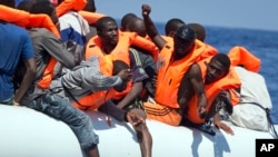 FILE - Migrants wearing life vests float in an inflatable boat during a rescue operation from the Aquarius vessel of SOS Mediterranee NGO and MSF (Doctors Without Borders) in the sea some 25 Nautical miles (29 miles, 46 kilometers) north of the Libyan coast, Aug. 27, 2017.