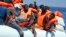 FILE - Migrants wearing life vests float in an inflatable boat during a rescue operation from the Aquarius vessel of SOS Mediterranee NGO and MSF (Doctors Without Borders) in the sea some 25 Nautical miles (29 miles, 46 kilometers) north of the Libyan coast, Aug. 27, 2017.