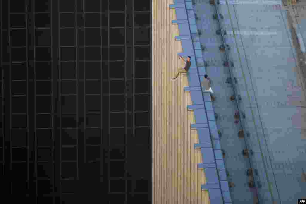 Two men take a series of selfies as they sit on the ledge of a high-rise building in an activity called &quot;rooftopping&quot; in Hong Kong, Aug. 23, 2016.