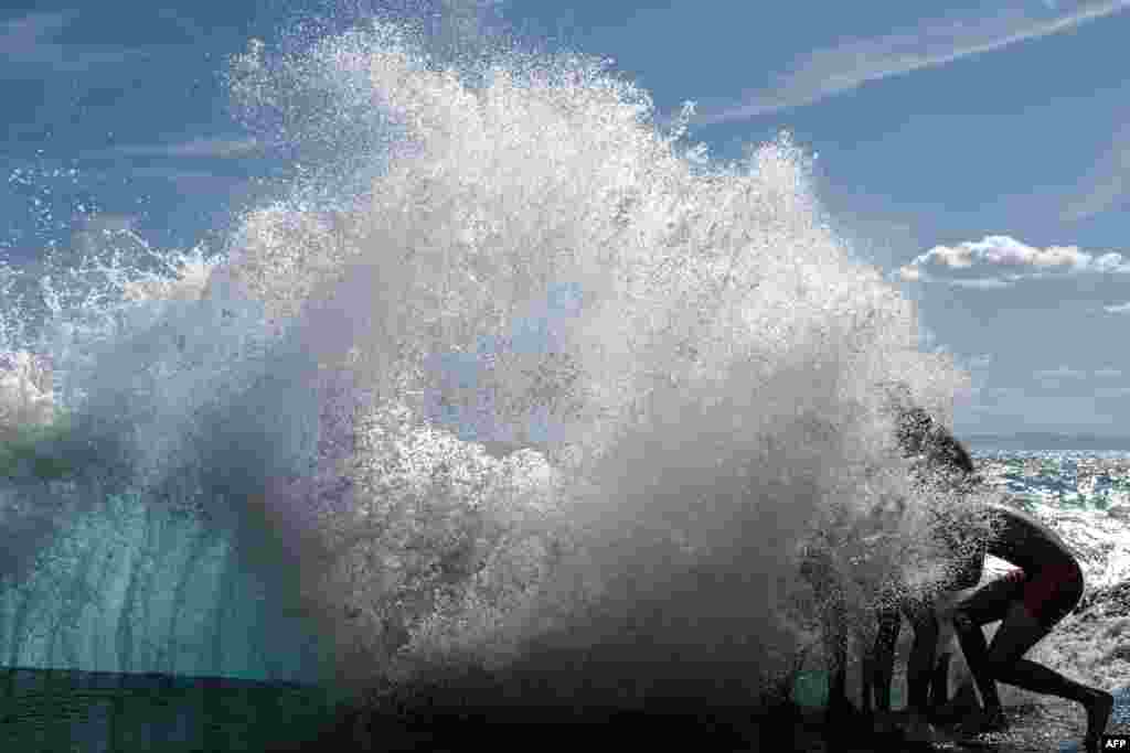 People play in the waves of the Mediterranean Sea in Nice, France.