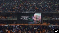Spectators shelter under umbrellas as the rain lashes down during the memorial service for former South African president Nelson Mandela at the FNB Stadium in Soweto, near Johannesburg, South Africa, Dec. 10, 2013.