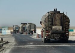 FILE - A convoy of oil tanker trucks pass a checkpoint on a highway in Hassakeh province, Syria, April 4, 2018.