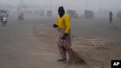 ARCHIVO - Una barredora limpia el área mientras el smog envuelve la zona y reduce la visibilidad en Lahore, Pakistán, el 11 de enero de 2024.