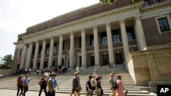 Orang-orang berjalan melewati pintu masuk Perpustakaan Widener, di belakang, di kampus Universitas Harvard, di Cambridge, Massachusetts, 16 Juli 2019. (Foto: AP)