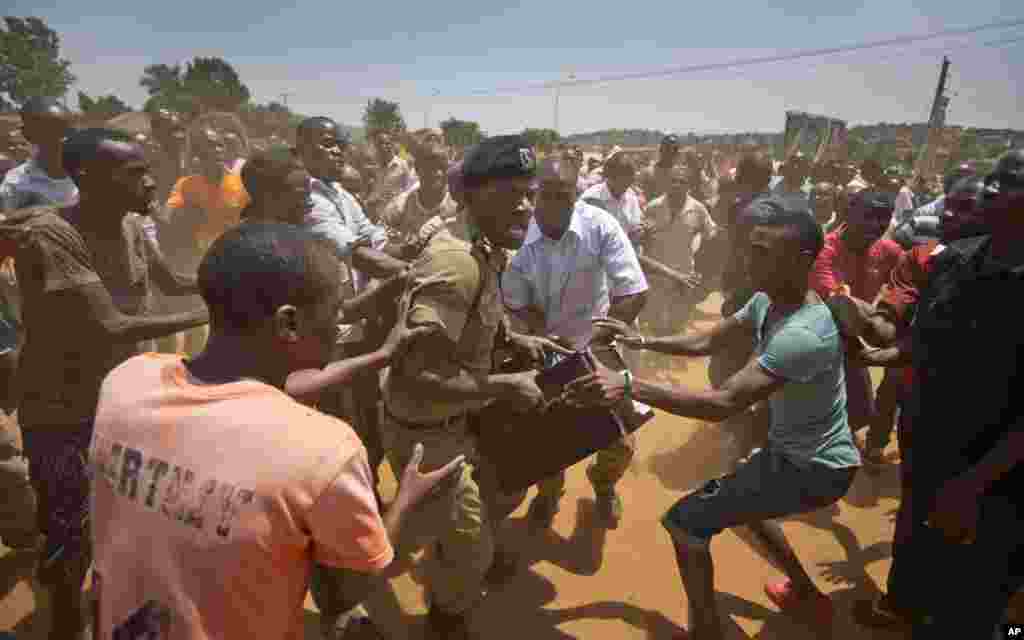 Un policier ougandais s'efforce de garder une boîte contenant du matériel de vote, alors que des électeurs l'entourent, en Ouganda, le 18 février 2016.