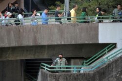 A riot policeman stands as voters line up outside a polling place in Hong Kong, Nov. 24, 2019. Voting was underway Sunday in Hong Kong elections that have become a barometer of public support for anti-government protests.