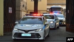 FILE - A police convoy escorts two buses with tinted windows leaving the high-security Lefortovo Prison in Moscow, Russia, Sept. 7, 2019.