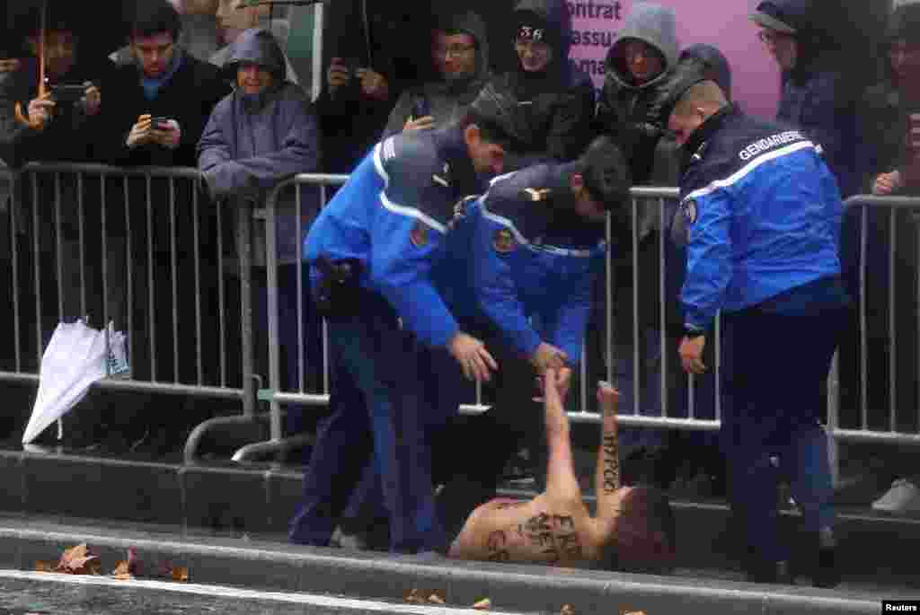 Police officers detain a protester who tried to jump into the motorcade of U.S. President Donald Trump on his way to the commemoration ceremony for Armistice Day, 100 years after the end of World War I at the Arc de Triomphe, in Paris, France.