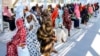 (FILE) Women with children wait in the shade to receive medical care outside the Italian Paediatric Hospital in Port Sudan on October 8, 2024.