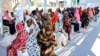 FILE - Women with children wait in the shade to receive medical care outside the Italian Paediatric Hospital in Port Sudan on Oct. 8, 2024.