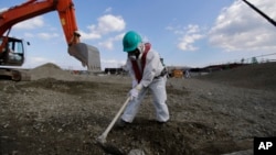 A worker, wearing a protective suit and a mask, levels ground at the tsunami-crippled Fukushima Dai-ichi nuclear power plant, operated by Tokyo Electric Power Co. (TEPCO), in Okuma, Fukushima Prefecture, northeastern Japan, Feb. 10, 2016.