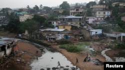 FILE - Kids jump on tires over a sewage in a slum in Freetown, Sierra Leone.