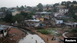 FILE - Kids jump on tires over a sewage in a slum in Freetown, Sierra Leone.