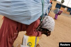 FILE - A Moroccan woman rests as she carries goods to be taken across the border from Spain's North African enclave of Melilla into Moroccan settlement of Beni Ansar, in Melilla, Spain, July 19, 2017.