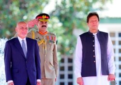 FILE - Visiting Afghan President Ashraf Ghani, left, reviews guard of honor with Prime Minister of Pakistan Imran Khan in Islamabad, Pakistan, June 27, 2019, in this photo released by the Press Information Department.