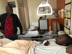A visitor talks to Tatenda Mombeyarara of Citizens Manifesto in a private hospital in Harare, Aug. 21, 2019. (C. Mavhunga/VOA)