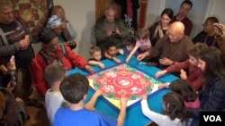 Children participate in the mandala dismantlement ceremony that follows the completion of the art. (VOA/ J. Soh)