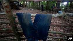 A Thai Border patrol police officer walks behind a pair of jeans left at abandoned migrant camp on Khao Kaew Mountain near the Thai-Malaysian border in Padang Besar, Songkhla province, southern Thailand, Tuesday, May 5, 2015. Police have found a recently 
