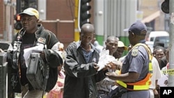 Zimbabweans pass a police cordon to submit their application forms in a last-minute bid to have their status in South Africa legalized, outside the Immigration offices in Johannesburg, Dec 31, 2010