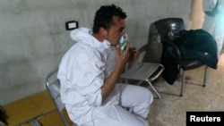 Arhiva - Čovek diše kroz masku za kiseonik nakon onoga što su spasioci opisali kao napad gasom, u Kan Šeikunu, Idlib, Sirija, 4. aprila 2017.