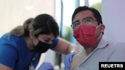 FILE - Jose Espinoza, 27, receives a vaccine against the coronavirus disease at a COVID-19 vaccination clinic in Los Angeles, California, Aug. 17, 2021.