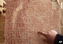 An official points to ancient South Arabian script at the Awwam Temple, also known as the Mahram Bilqis, in Marib, Yemen, Feb. 3, 2018.