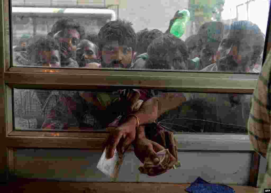 Laborers buy bus tickets at a counter of Jammu and Kashmir Tourist Reception Centre (JKTRC) in Srinagar, India. A protester died after being chased by police during a curfew in Kashmir's main city, left in turmoil by an Indian government move to tighten control over the restive region, a police official said.