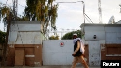 FILE - A man walks past the front gate of the International Committee of the Red Cross (ICRC) office in Jalalabad province, June 2, 2013