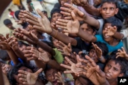 Rohingya Muslim children, who crossed over from Myanmar into Bangladesh, stretch their arms out to collect chocolates and milk distributed by Bangladeshi men at Taiy Khali refugee camp, Bangladesh, Sept. 21, 2017.