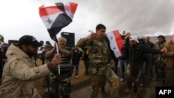 Syrian volunteers and relatives wave the national flag and portraits of President Bashar al-Assad as they celebrate at the end of paramilitary training conducted by the Syrian army in al-Qtaifeh, near Damascus, Feb. 22, 2016.