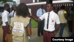 A student checks temperatures of students and visitors before schools open in Liberia