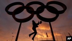 FILE - A woman poses with the Olympic rings in Olympic Park, Feb. 5, 2014. The Olympic Channel will launch officially Aug. 21, 2016.