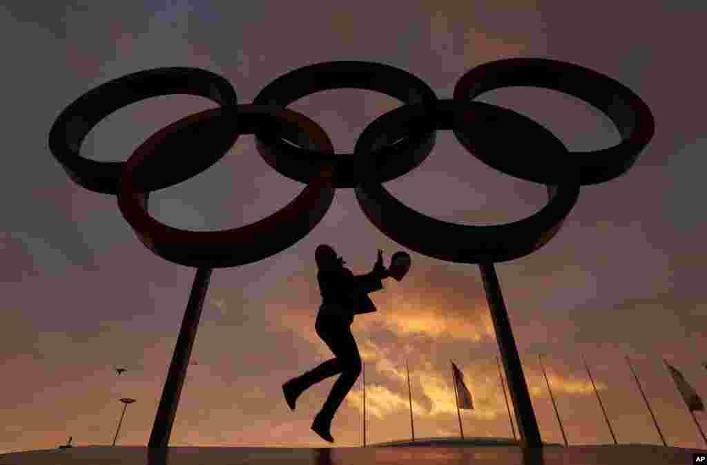 A woman poses with the Olympic rings in Olympic Park as preparations continue for the 2014 Winter Olympics, Feb. 5, 2014.
