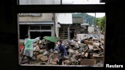 Warga membersihkan puing-puing yang terbawa banjir akibat hujan lebat di Hitoyoshi, Kumamoto Prefecture, Jepang barat daya, 9 Juli 2020.