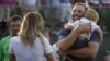 Dustin Johnson, right, greets his fiancée Paulina Gretzky as he holds their son Tatum Gretzky on the 18th hole during the final round of the U.S. Open golf championship at Oakmont Country Club on Sunday, June 19, 2016.