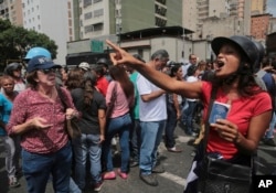 A government supporter holds a copy of Venezuela's constitution as she argues with opposition members outside the Supreme Court where opposition protesters gathered to show support for chief prosecutor Luisa Ortega Diaz.