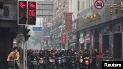 တရုတ်နိုင်ငံ၊ ရှန်ဟိုင်းမြို့လယ်ခေါင် မီးပွိုင့်တစ်ခုတွင် စောင့်ဆိုင်းနေကြသည့် မော်တော်ဆိုင်ကယ်၊ စက်ဘီးစီး ဒေသခံများ။ ဒီဇင်ဘာ ၆၊ ၂၀၁၃။