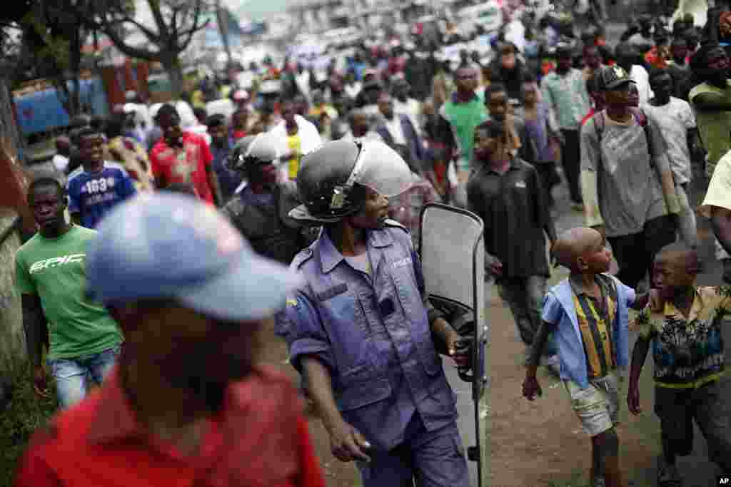 Congolese policeman in riot gear keeps an eye on Goma residents, including street children, who gathered for an anti-Kabila demonstration supported by the M23 rebel movement in Goma, DRC, November 28, 2012. 