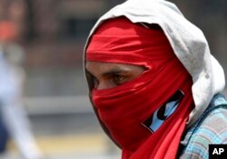 A masked demonstrator keeps his eyes on a group of Bolivarian National Guard officers during a protest in Caracas, Venezuela, April 10, 2017.