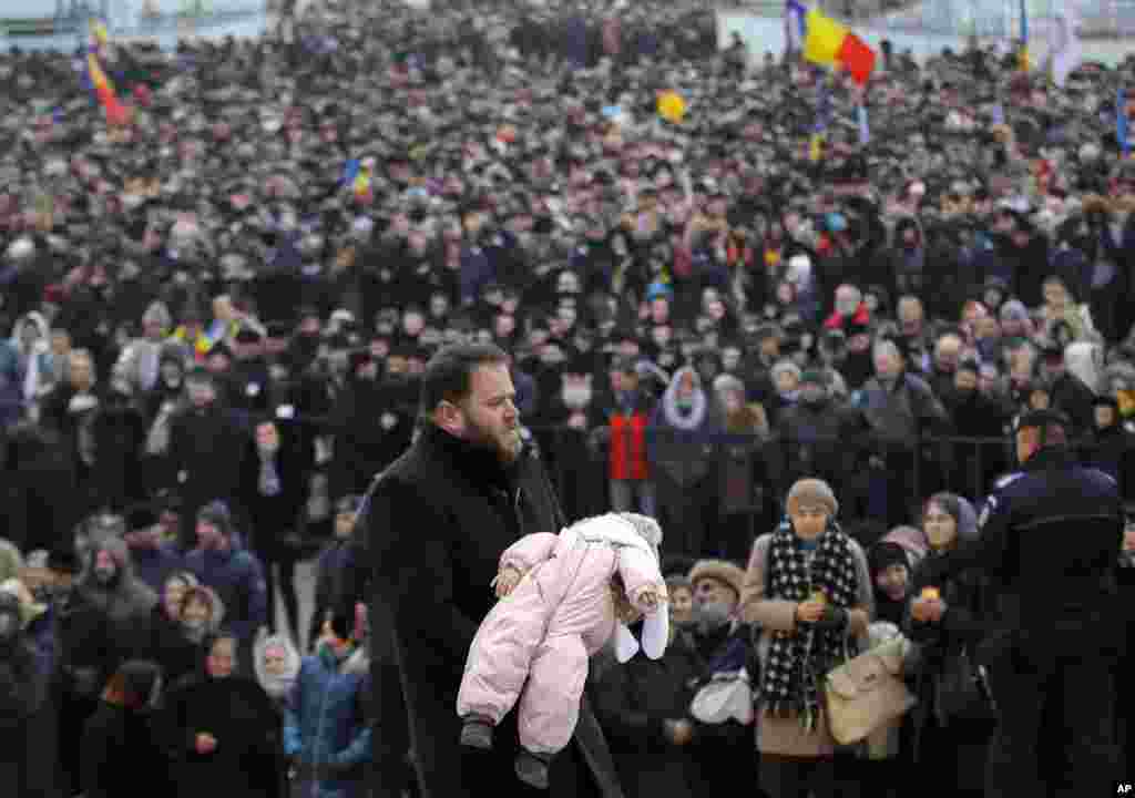 루마니아&nbsp;부쿠레슈티의 국립성당에서 남성이&nbsp;성찬을 받을 아이를 안은 채 걷고 있다.