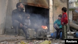 A man and children sit around a fire in the besieged area of Homs, Jan. 30, 2014. 