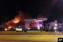 Authorities respond near a burning gas station as dozens of people protest following the fatal shooting of a man in Milwaukee, Aug. 13, 2016.