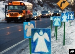 FILE - A bus traveling from Newtown, Connecticut, to Monroe stops in front of 26 angels along the roadside on the first day of classes for Sandy Hook Elementary School students since the December 14 shooting.