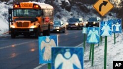 A bus traveling from Newtown, Connecticut, to Monroe stops in front of 26 angels along the roadside on the first day of classes for Sandy Hook Elementary School students since the December 14 shooting.